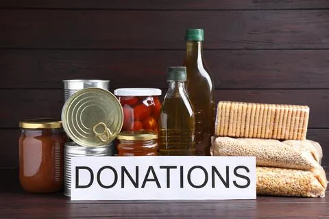 Card with word Donations and different products on wooden table Stock Photos