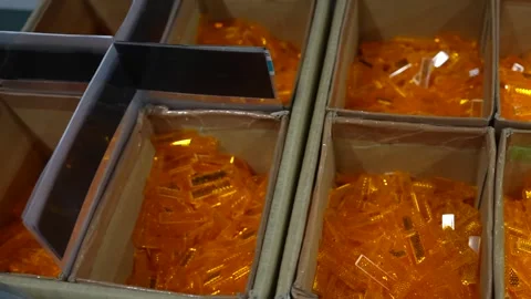 Cardboard bins filled with orange translucent injection molded plastic parts Stockbeeldmateriaal 340901917