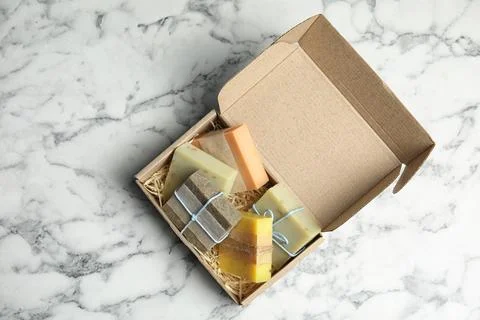 Cardboard box with different handmade soap bars on table, top view Foto stock