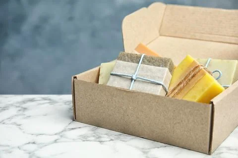 Cardboard box with different handmade soap bars on table. Space for text Foto stock