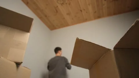 A cardboard box is in sharp focus while a young man in the background joyfully Stock Footage 304636509