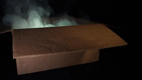 A cardboard box from which smoke comes and light shines. Concept of sorcery and Video stock 129743734