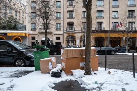 Cardboard boxes and garbage bin on snow-covered Avenue George V in Paris, France Foto stock