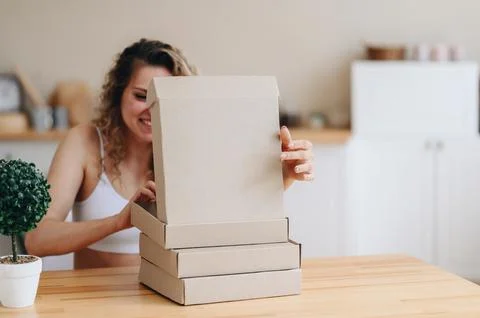 Cardboard Boxes Are Stacked On The Table. A Woman Opens a Box with a Smile. R Stock Photos