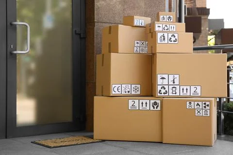 Cardboard boxes with different packaging symbols on porch near entrance. Parc 스톡 사진