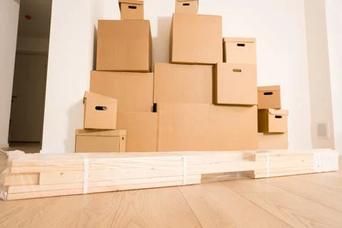 Cardboard boxes of different sizes stack against white walls Stock-Fotos