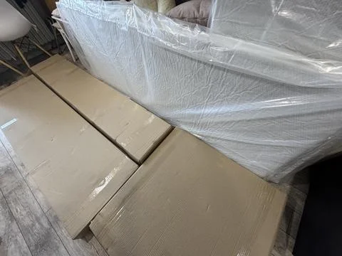 Cardboard boxes with ottoman assembly elements. Nearby are orthopedic mattres Stock Photos