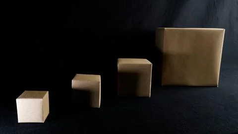 Cardboard boxes showing size progression on dark background Stock Photos