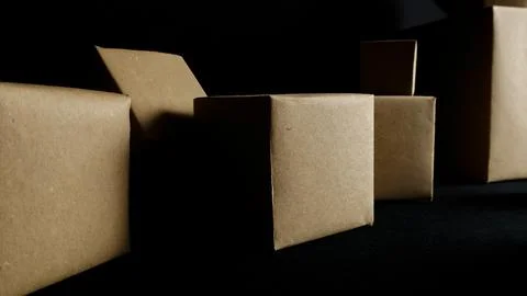 Cardboard boxes standing on dark background creating shadows Stock Photos