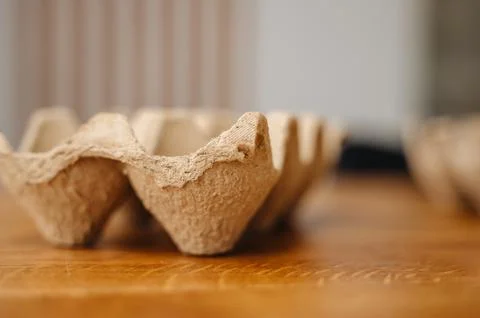 A cardboard egg tray placed on a rustic wooden table Stock Photos