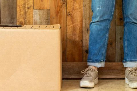 Cardboard moving boxes in empty room with wooden wall background and copy space Stock Photos