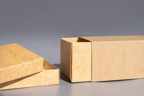 Cardboard packaging box set with open lid on gray background. International.. Stock Photos