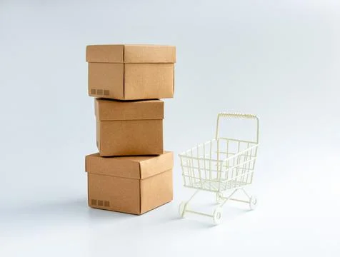 Cardboard parcel boxes stack and empty shopping trolley cart isolated on whit Stock Photos