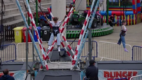 CARDIFF, UK - AUGUST 8, 2025 - Girls jumping on bungee trampoline in Cardiff, Stock Footage 314802418