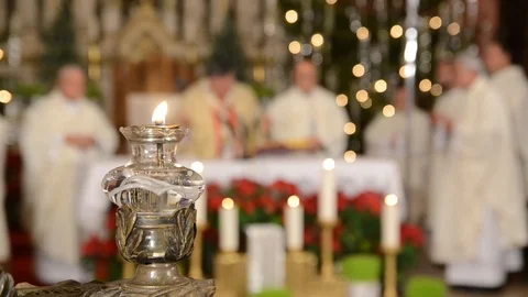 Cardinal and priest in front of the altar in catholic church. Lit candle. Video stock 121997281