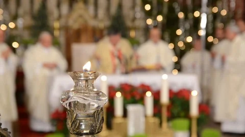 Cardinal and priests in front of altar in church. Lit candle. Christmas mass Stock Footage 121997133