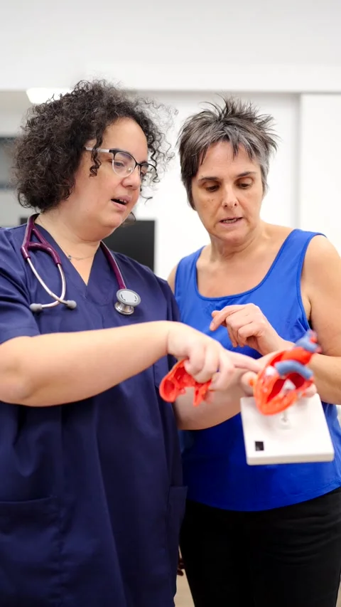 Cardiologist explaining procedure to a patient using a heart model Stock Footage 260656606