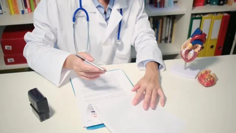 Cardiologist sitting at the table and explain the disease in hospital Stock Footage 251941059