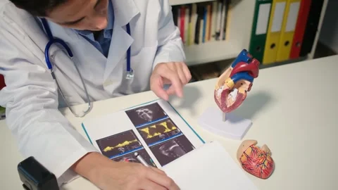Cardiologist sitting at the table and explain the disease in hospital Stock Footage 251941094