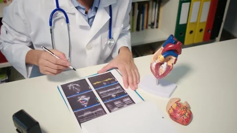 Cardiologist sitting at the table and explain the disease in hospital Stock Footage 251941110