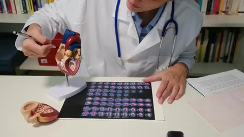 Cardiologist sitting at the table and explain the disease in hospital Stock Footage 251941330