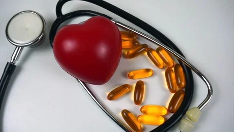 Cardiology concept with a hand placing a red heart near a stethoscope and fish Stock Footage 333772013