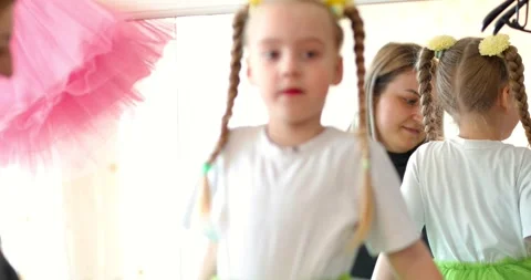 Care of a dance instructor or mother adjusting a bright green tutu on a young Video stock 305896736
