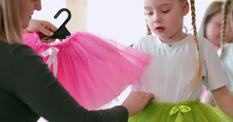 Care of a dance instructor or mother adjusting a bright green or pink tutu Video stock 305896804