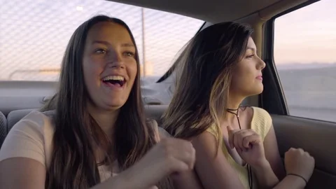 Carefree Road Trippers Dance In Back Seat Of Car, On Freeway, At Sunset Stock Footage 76971035