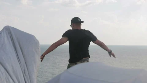 Carefree, young, amicable dude stands on a cliff above the sea and enjoys. 動画素材 93486109