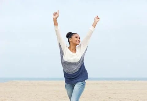 Carefree young woman with arms outstretched walking on the beach Stock Photos