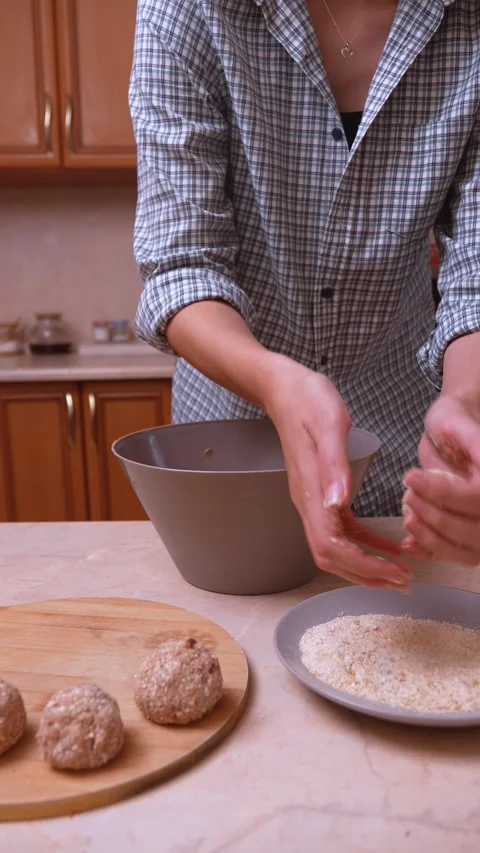 Careful breading of meatballs next to serving dishes in process Stock Footage 330023139