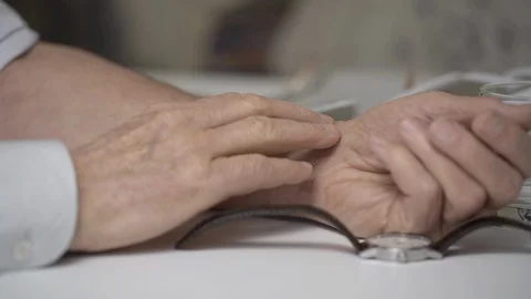 Careful elderly man measures pulse with watch at white table Vídeo Stock 127424757