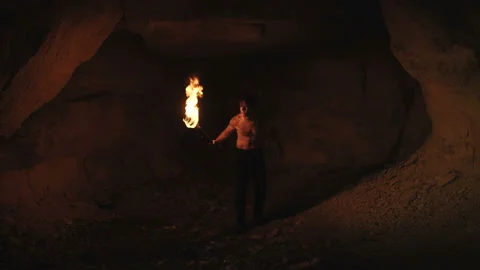 Careful hermit with burning torch in hand walks and looks around in stone cave Video stock 88003341