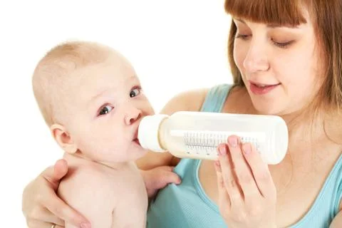 Careful mother holds bottle of milk while her adorable baby drinking it Stock Photos