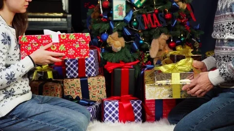 Careful parents placing bright git boxes filled with Christmas presents under Stock Footage 98698012