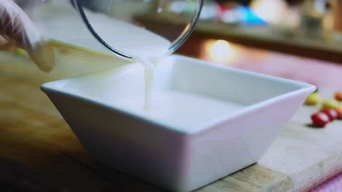 Careful serving study of steady custard stream entering the square mold Stock Footage 342154041
