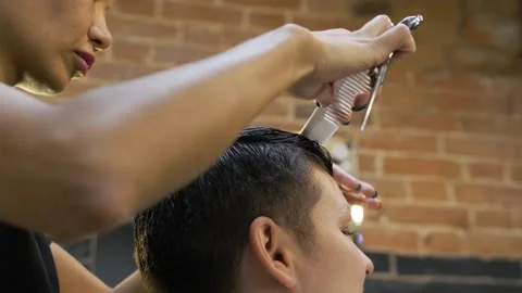Careful work with a comb parting the black hair on the head of a sitting woman Stock Footage 258051038