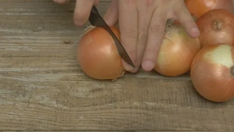 Carefully Chopping Onions with a Sharp Knife on a Sturdy Wooden Surface in the Stockbeeldmateriaal 282665272