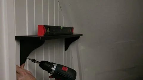 Carefully drilling wall shelf bracket into place Stock Footage 325840192