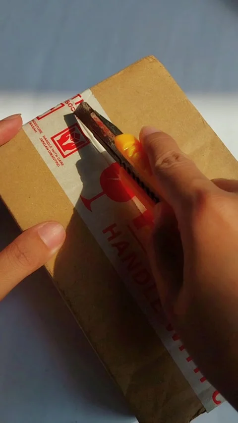 Carefully opening a fragile package labeled Fragile or not to be thrown. Ha.. Stockbeeldmateriaal 330749298