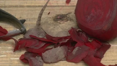 Carefully peeling beetroot using a kitchen tool while it rests on a rustic Stock Footage 280692855