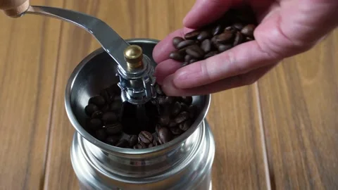 Carefully pouring coffee beans into a manual hand coffee grinder Stock-Footage 197755885