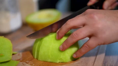 Carefully Slicing Fresh Yellow Melon on an Elegant Wooden Cutting Board Stock Footage 283486220