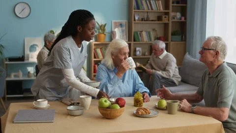 Caregiver Clearing Breakfast Table at Senior Living Home Video stock 306926838