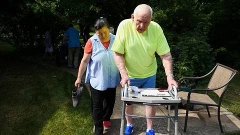 A caregiver helping an elderly man with a walker Stock Footage 77374425