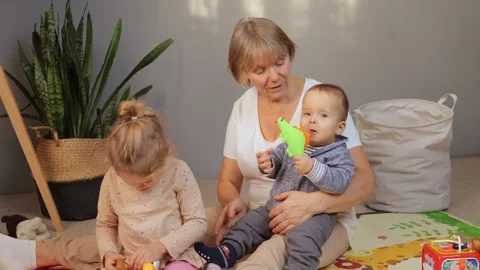 A caregiver interacts playfully with two young children, fostering creativity Stock-Footage 295849072