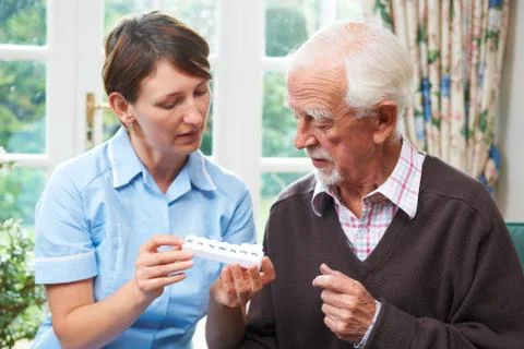 Carer Helping Senior Man With Medication Stock Photos