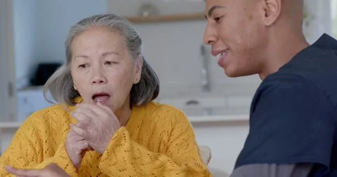 Carer pointing at tablet explaining meds, Senior Chinese woman yellow listening Vídeo Stock 345509416