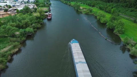 A cargo barge floats on a river through a field and a sand pit Stock Footage 154375933